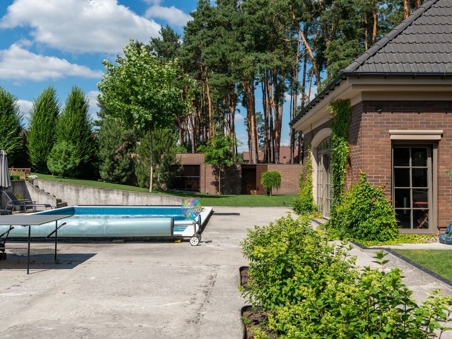 Concrete pool deck and patio beside a backyard pool